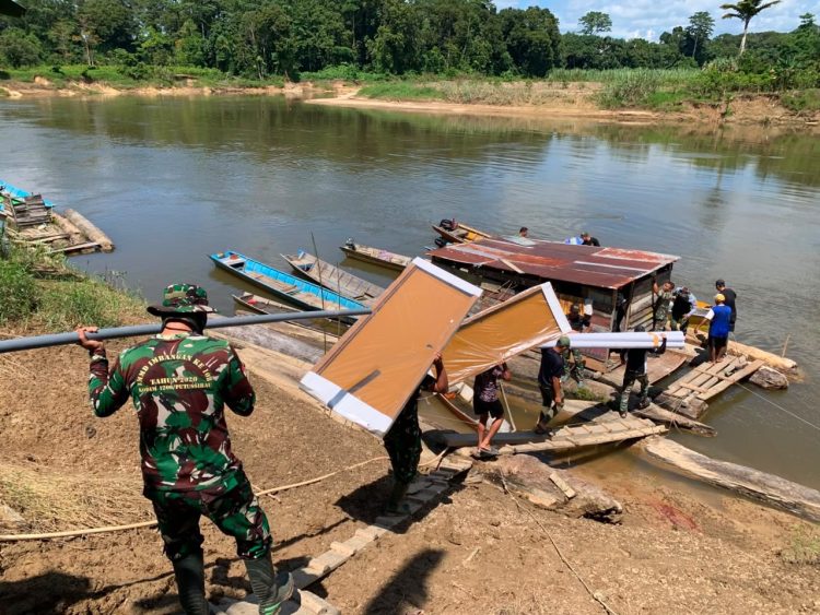 Semangat Anggota Satgas TMMD Kodim 1206/Putussibau Saling Bahu-Membahu Naikkan Material Bangunan ke Perahu Menuju Desa Belatung